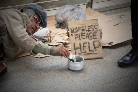Homeless senior adult man sitting and begging in overpass