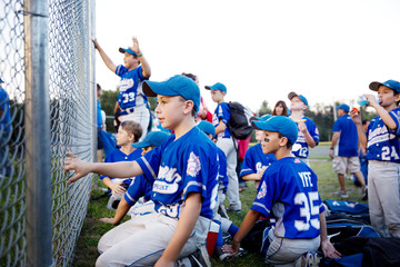 Little league team (8-9, 10-11) cheering from behind fence