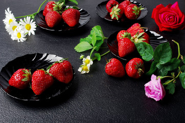 Red strawberries on black saucers on a dark table surrounded by daisies - Powered by Adobe