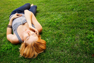 Young woman listening to music while lying on grass 