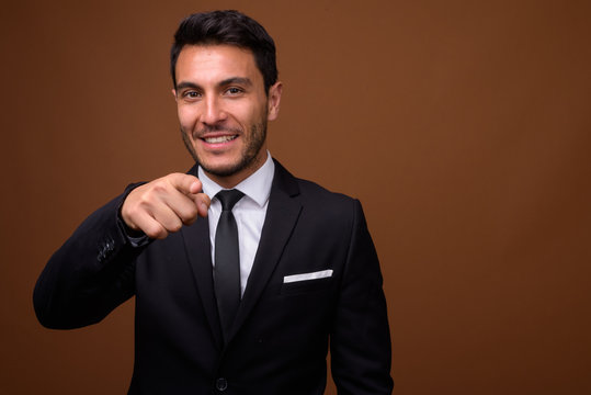 Young Handsome Hispanic Businessman Against Brown Background