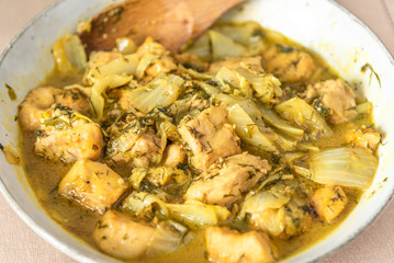 Chicken with Chinese cabbage in curry sauce in a bowl on a light background - a traditional Asian dish