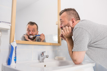 Bored guy brushing his teeth in bathroom