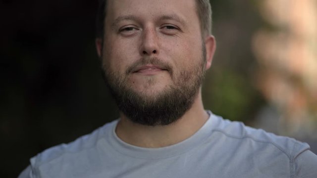 Bearded man drinking takeaway coffee on the street and smiling. close-up
