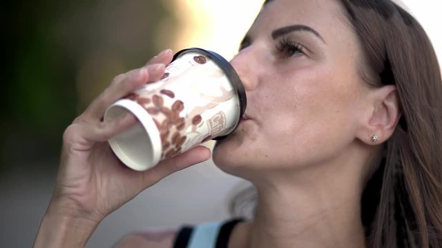 beautiful young Caucasian woman drinking takeaway coffee on the street. Beautiful girl on the street with coffee smiling and enjoying. close-up