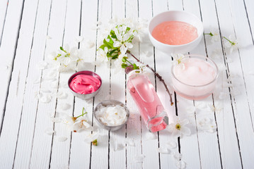 beauty products and cherry blossom on white wood table