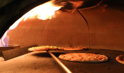 fire and pizza inside an oven in the pizzeria