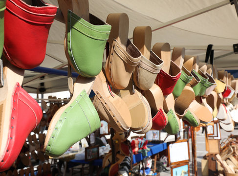 wooden and leather clogs hanging on sale in the stall of handmad
