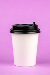 Paper coffee container with black lid on a purple background. Beverage container take-away. Drink Cup template for your design