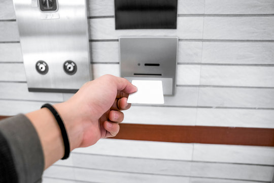 securing lift or elevator access control, man's hand is holding a key card lay up to insert in card hold for unlocking elevator doors before up or down.