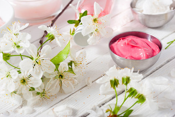 beauty products and cherry blossom on white wood table