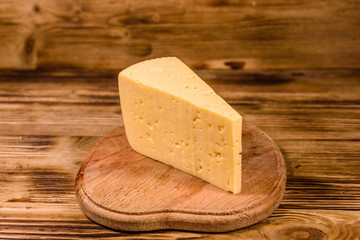 Cutting board with piece of cheese on wooden table