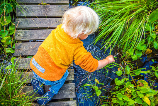 Blonde Boy Playing At Small Creek In Swedish Nature