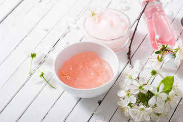 beauty products and cherry blossom on white wood table