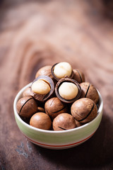 Macadamia nuts in a bowl on wooden background