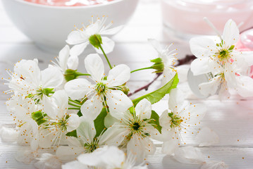 beauty products and cherry blossom on white wood table