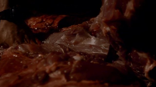 Slow Motion of aboriginal man cuts skin pork carcass in slaughter. Processing of dissecting pigs carcasses on farm night. Pork meat production. Freshly slaughtered pig carcass-Dan