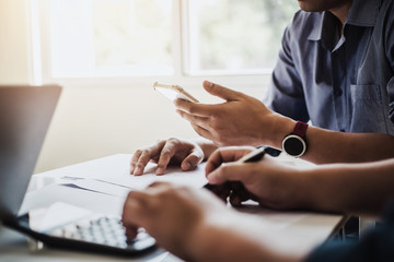 Architect or engineer reading message on phone during the meeting building plan design project in office. Construction engineering tools and structure concept.