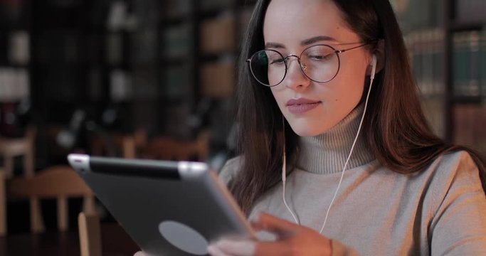 Female university student typing on tablet in library