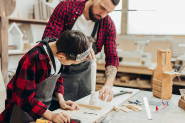profession, carpentry, woodwork and family concept - carpentery masterclass for little children and their fathers to share basic knowledge of working with wood.