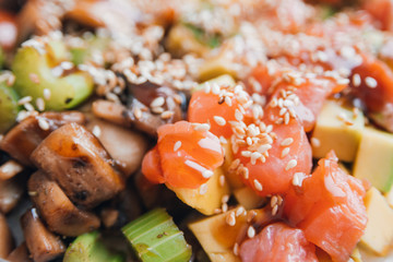 Poke bowl of rice with avocado, mushrooms and salmon closeup