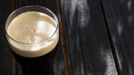 Cold glass of dark stout beer on wooden table