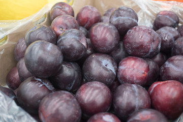 Texture of red plum in shop close up top view. Box with plums in store. Tasty sweet fruit for dessert, salad, juice.