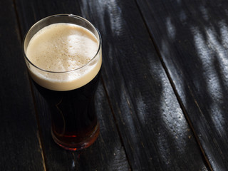 Pint of dark stout beer on wooden background