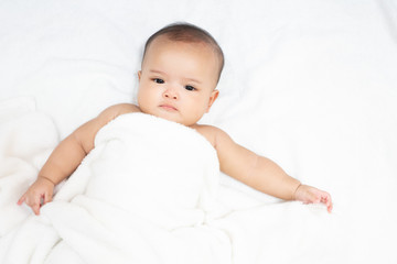 Happy Asian newborn baby under white towel after bath