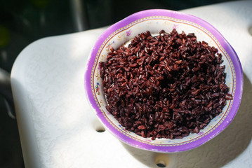 Black rice in a bowl put on the chair under sunlight in a kitchen