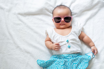 Asian baby girl wearing swimingsuit and pink sunglasses on white background, baby in beach wear fashion