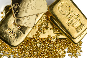 A few different gold bar on a pile of gold granules. Isolated on a white background.