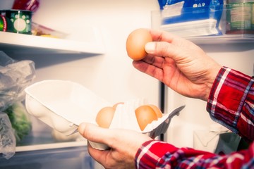 Fototapeta premium man taking eggs from the fridge, concept of diet and food