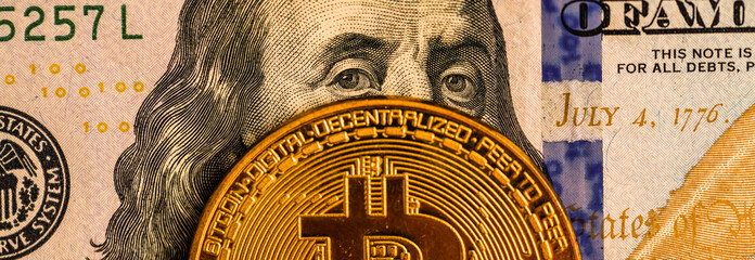 Gold Bitcoin on hundred dollars bills. Close-up, macro shot.