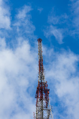 Antenna tower with blue sky and cloud background.