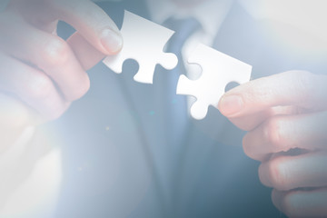 Business solutions. business man holds two pieces of puzzle together