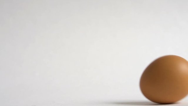 Egg are rolling on the white table. Easter eggs background. Can be used as looped.
