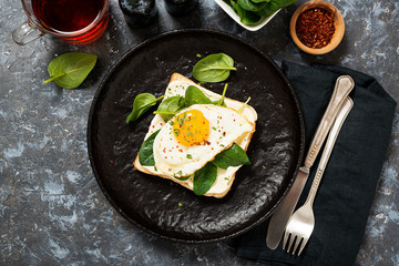Toast with cream cheese, spinach and fried egg, top view.