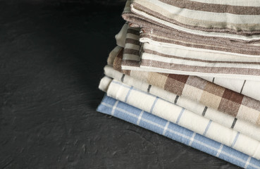 Stack of fabric napkins on black table, space for text