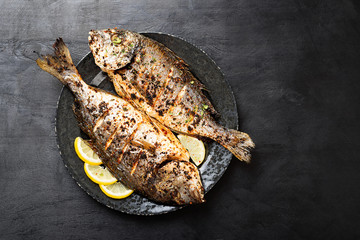 Tasty grilled fish dorado with  lemon on kitchen table.