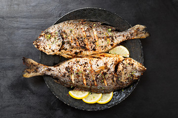 Tasty grilled fish dorado with  lemon on kitchen table.
