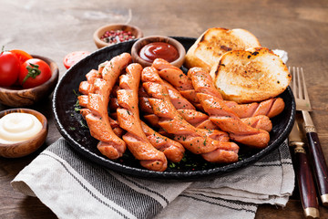 Grilled sausages and different sauce on a dark wooden background.