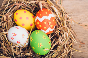 Fototapeta na wymiar Beautiful Easter multi color egg in straw on wooden