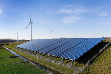 Solar panels and wind turbines generating eco friendly green energy for a better environment near...