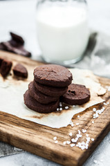 A stack of chocolate cookies with milk on a wooden board