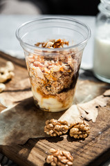 Nutty dessert in a glass on a wooden board with a bottle of milk