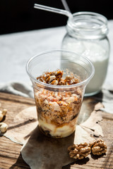 Nutty dessert in a glass on a wooden board with a bottle of milk