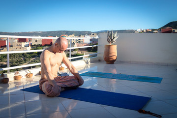 A girl and a man practice yoga on a flat roof at Dawn. Africa Morocco Agadir