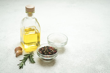 Fresh rosemary herb with oil and spices on a light background.