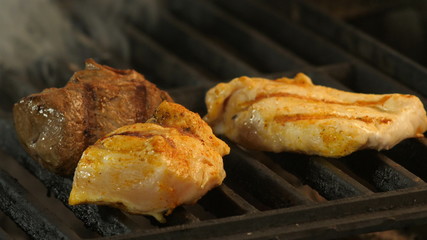 Grilled meat, two chicken fillets or turkey meat with grill prints and veal meat are medalled roasted on the grill, in the background are smoke tubers. Macro photography